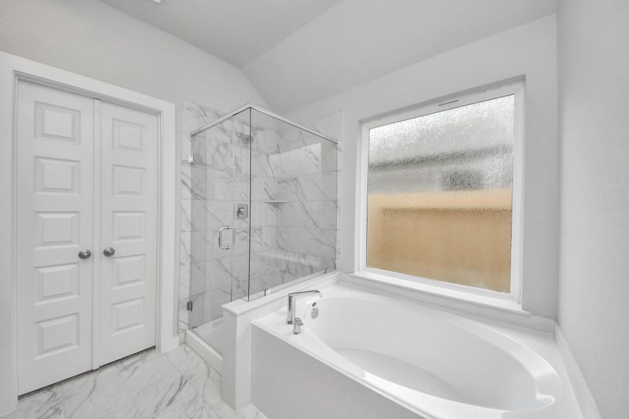 Indulge in a spa-like retreat within the confines of this primary bathroom. Delight in a spacious walk-in shower enveloped in stylish tile surround and unwind in a separate garden tub adorned with custom detailing. Sample photo of completed home with similar floor plan. Actual colors and selections may vary. Indulge in a spa-like retreat within the confines of this primary bathroom. Delight in a spacious walk-in shower enveloped in stylish tile surround and unwind in a separate garden tub adorned with custom detailing. Sample photo of completed home with similar floor plan. Actual colors and selections may vary.