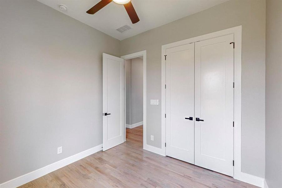 Unfurnished bedroom with light wood-type flooring, ceiling fan, and a closet