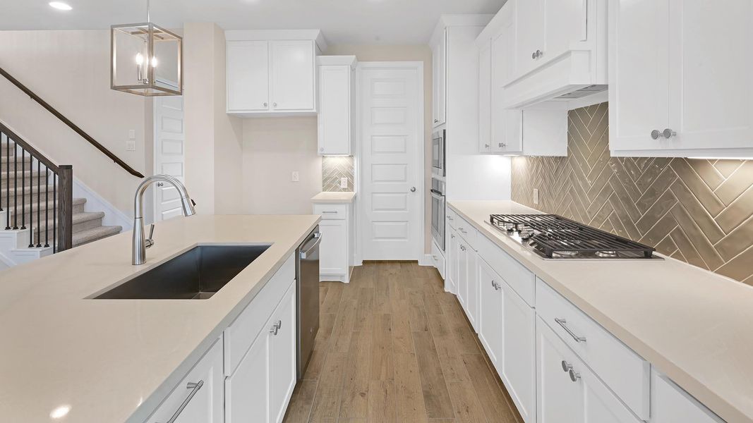 Kitchen featuring pendant lighting, light wood-style floors, backsplash, white cabinetry, and recessed lighting