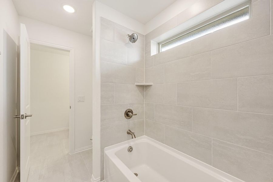 Bathroom with soaking tub, tiled shower surround, and small frosted window above Bathroom with soaking tub, tiled shower surround, and small frosted window above