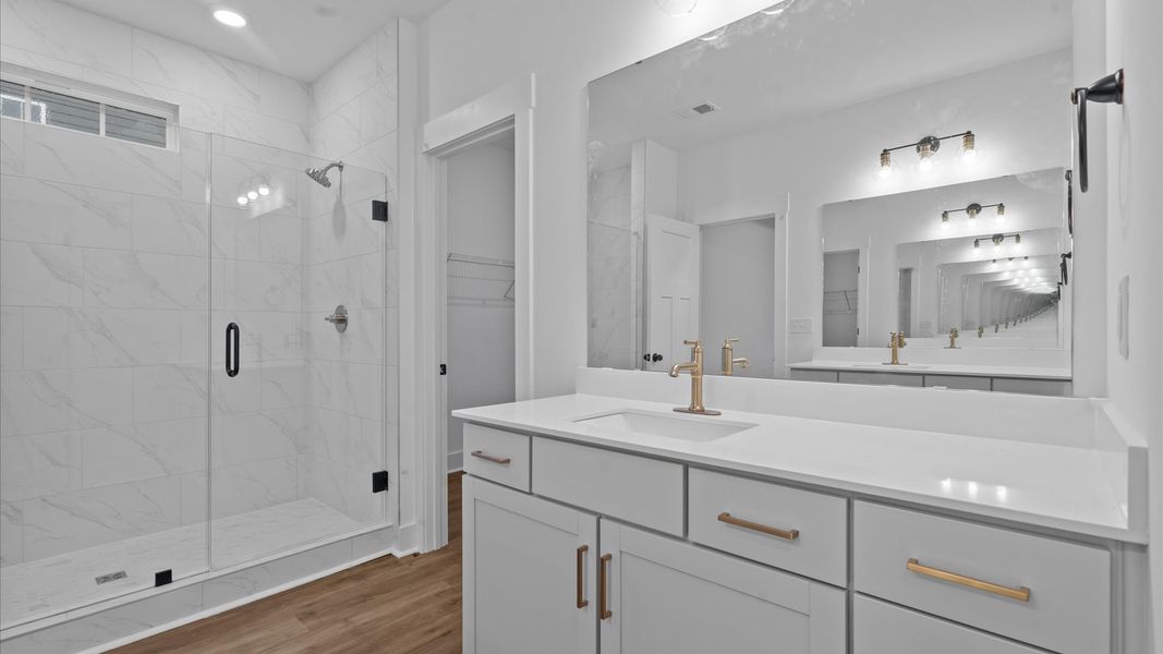 Memorable mornings begin in this elegant primary bathroom with walk-in shower and separate vanities