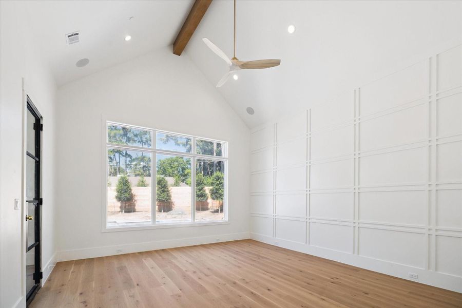 Primary bedroom overlooking the back yard and pool. Easy access to the pool/patio. Bright, spacious room with high vaulted ceilings, featuring large windows providing natural light. The room has elegant hardwood flooring and a stylish grid-patterned accent wall. Primary bedroom overlooking the back yard and pool. Easy access to the pool/patio. Bright, spacious room with high vaulted ceilings, featuring large windows providing natural light. The room has elegant hardwood flooring and a stylish grid-patterned accent wall.