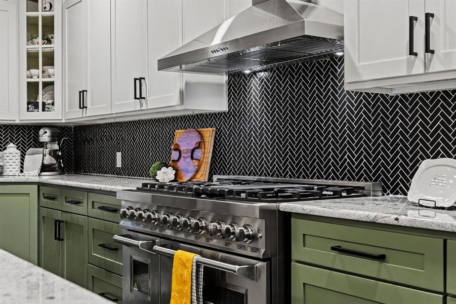 Kitchen featuring green cabinets, decorative backsplash, glass insert cabinets, and high end stainless steel range Kitchen featuring green cabinets, decorative backsplash, glass insert cabinets, and high end stainless steel range