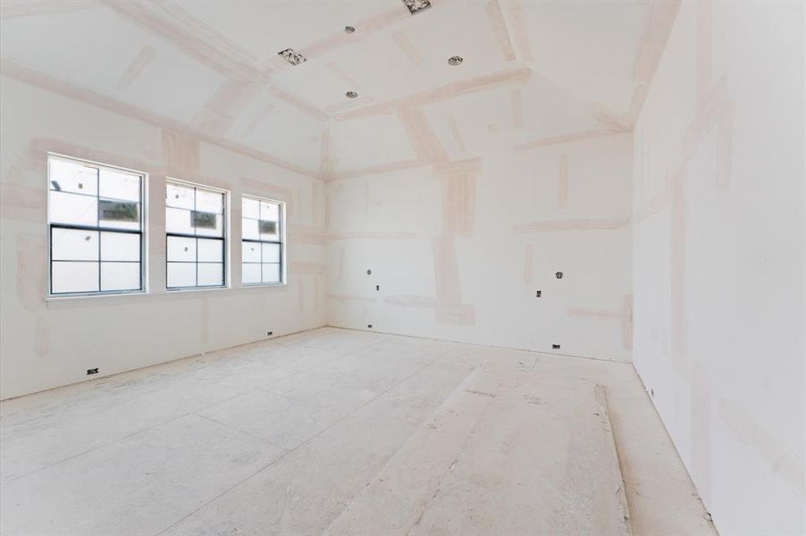 Spacious primary bedroom with 14' ceilings, bathed in natural light, invites serenity and relaxation. A small entryway creates a defined space perfect for art, before entering the primary bedroom.