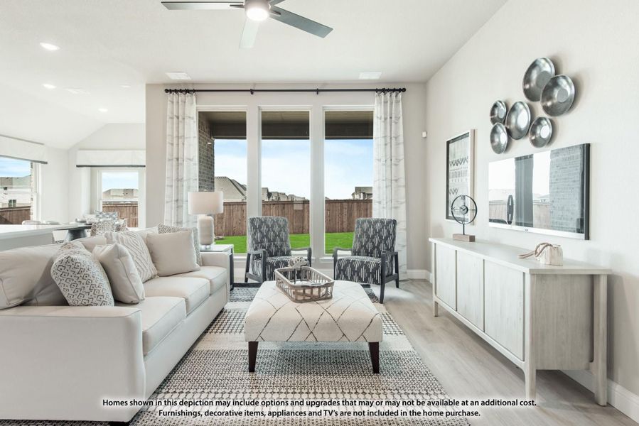 Bright living room with light gray sofa, accent chairs, hardwood floors, and large windows overlooking a backyard. Bright living room with light gray sofa, accent chairs, hardwood floors, and large windows overlooking a backyard.