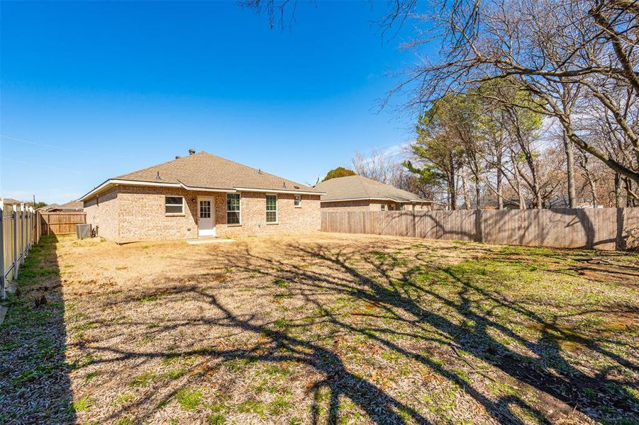 Back of property with a yard, brick siding, and a fenced backyard