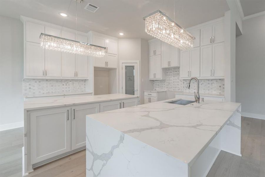 Kitchen featuring a center island with sink, light stone countertops, light wood-style flooring, and recessed lighting