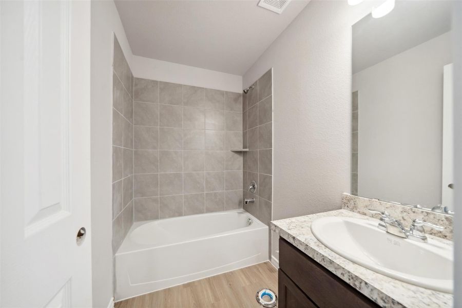 The first bathroom is bathed in natural light and features a spacious shower/tub combo.