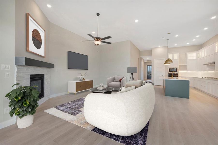 Living area featuring a glass covered fireplace, recessed lighting, light wood-style flooring, and a ceiling fan Living area featuring a glass covered fireplace, recessed lighting, light wood-style flooring, and a ceiling fan