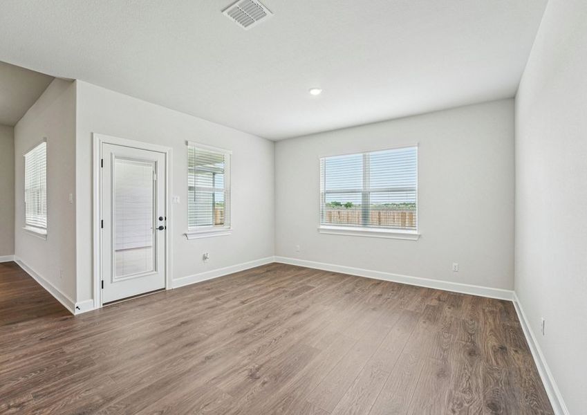 Open-concept family room featuring a ceiling fan, wood-look vinyl flooring, and a sightline into the kitchen and dining area. Open-concept family room featuring a ceiling fan, wood-look vinyl flooring, and a sightline into the kitchen and dining area.