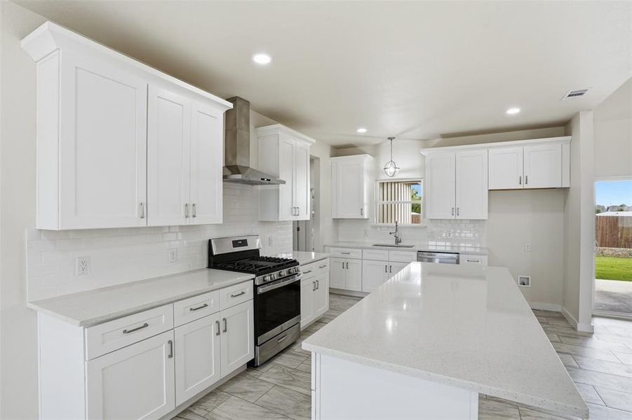 Bright kitchen featuring white shaker cabinetry, stainless steel appliances, white subway tile backsplash, light-toned countertops, and wood-finish tile flooring