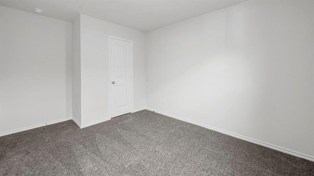 Carpeted room featuring a white interior door with a silver knob, white baseboards, and light-colored walls
