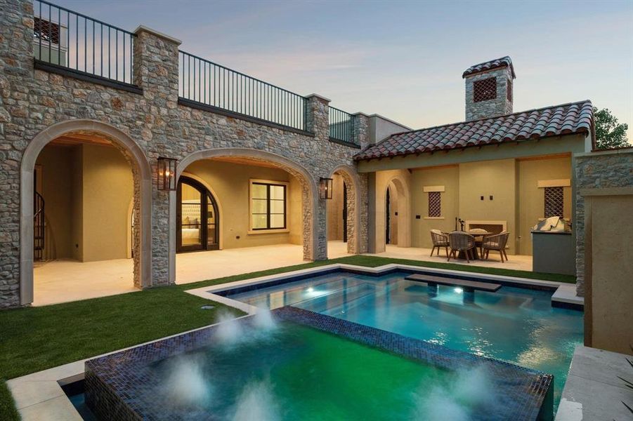 Courtyard view of house featuring a large balcony, a patio, a tile roof, and a pool with connected hot tub Courtyard view of house featuring a large balcony, a patio, a tile roof, and a pool with connected hot tub