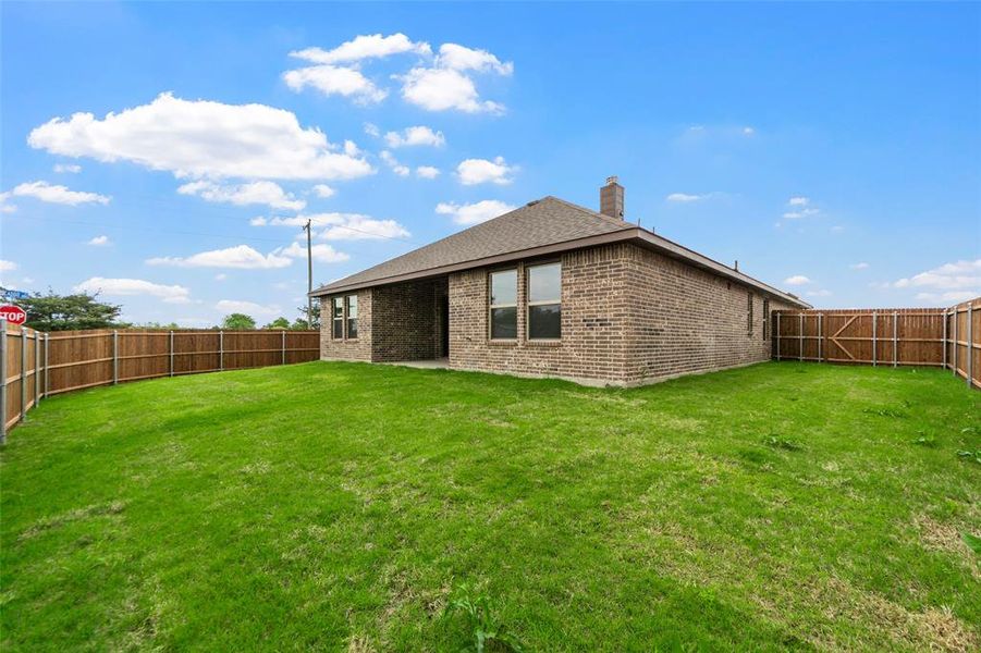 Spacious backyard featuring a full wood privacy fence and a brick-faced exterior