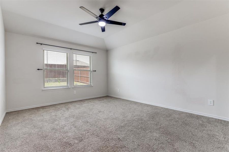 Carpeted interior space featuring a vaulted ceiling and a modern ceiling fan with integrated lighting Carpeted interior space featuring a vaulted ceiling and a modern ceiling fan with integrated lighting