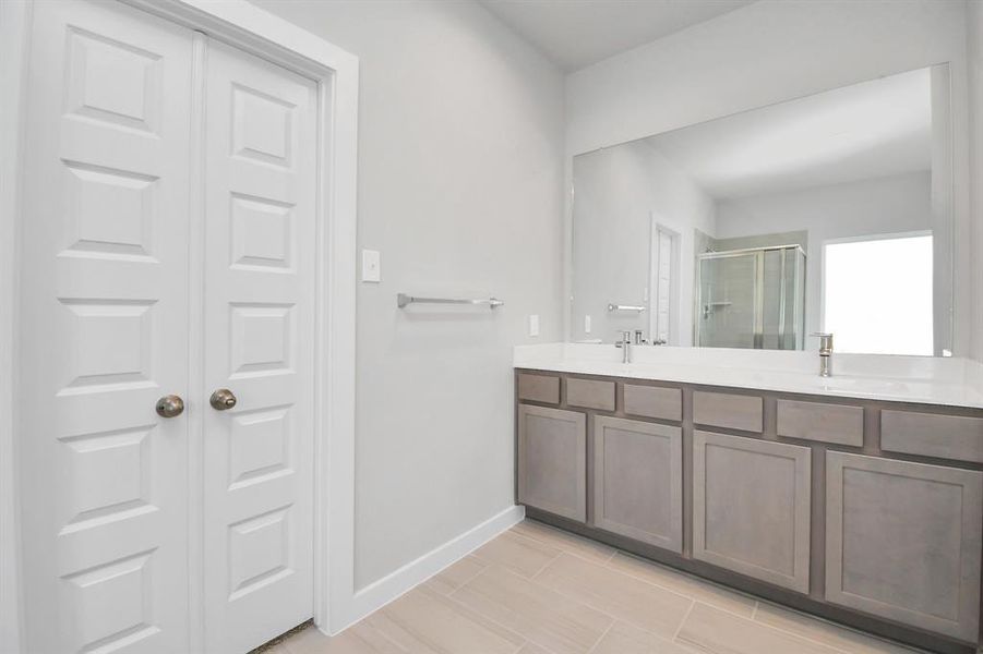 An elegant vanity featuring light countertops, modern hardware, and beautiful recessed lights. Experience luxury and relaxation in every . Sample photo of completed home with similar floor plan. Actual colors and selections may vary.