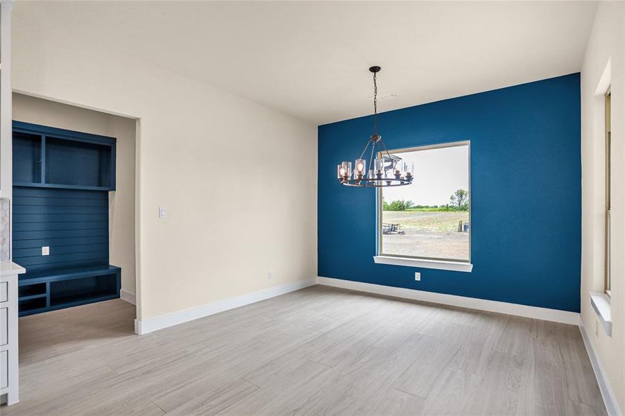 Unfurnished dining area featuring a chandelier and light wood-style floors Unfurnished dining area featuring a chandelier and light wood-style floors
