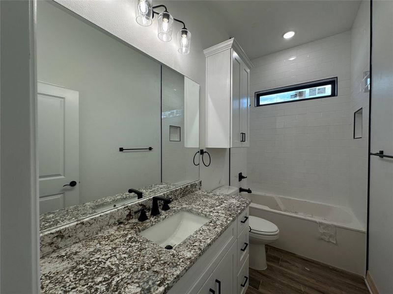 Bathroom featuring wood tiled floors, vanity, bathing tub / shower combination, and recessed lighting