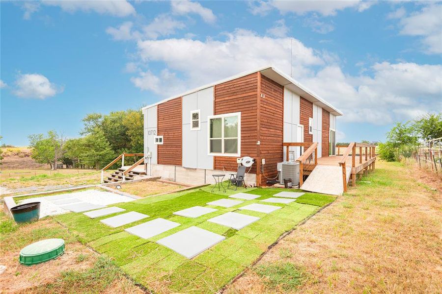Rear view of house featuring a wooden deck and a lawn Rear view of house featuring a wooden deck and a lawn