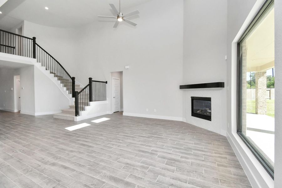 Relax and unwind in this inviting family room, illuminated by abundant natural light streaming in through tall windows, complemented by high ceilings and stunning flooring. Stay comfortable year-round with the gentle breeze from the ceiling fan, creating the perfect atmosphere for family gatherings. Sample photo of completed home with similar floor plan. Actual colors and selections may vary.