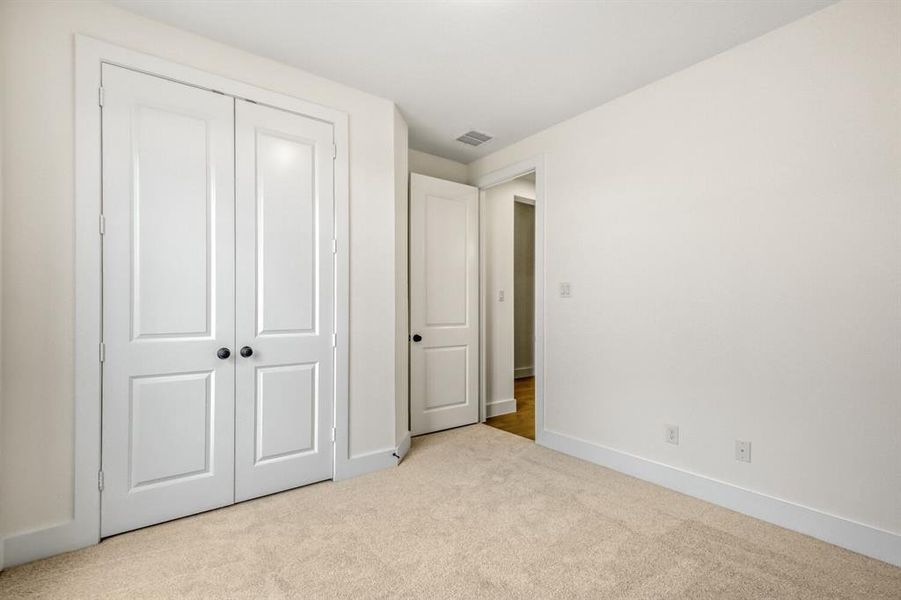 Unfurnished bedroom featuring light carpet and a closet