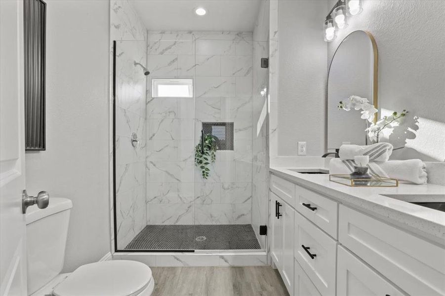 Bathroom with wood-type flooring, vanity, toilet, and a shower with door