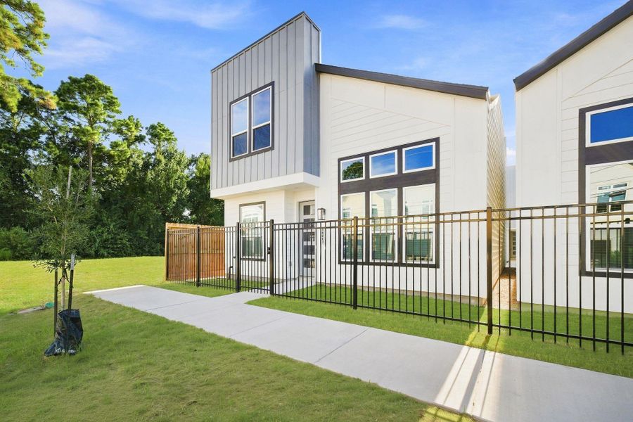 Street-level view showcasing the modern architecture, fenced front yards, sidewalks, and cohesive contemporary design throughout the community.