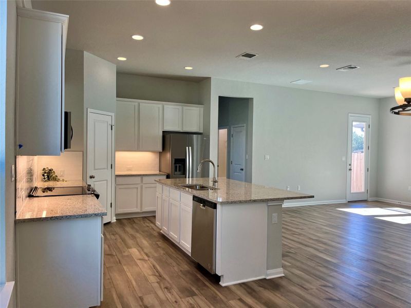 Kitchen featuring light stone countertops, appliances with stainless steel finishes, white cabinets, dark wood-type flooring, and recessed lighting
