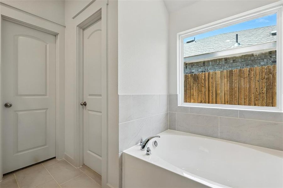 Full bath with a garden tub and light tile patterned floors