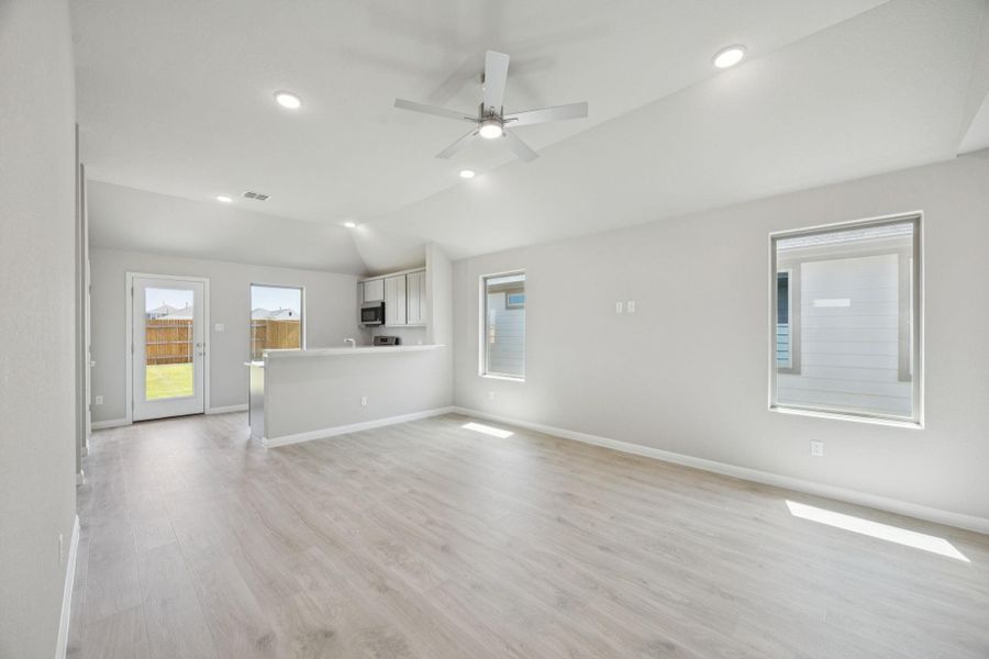 Unfurnished living room featuring light wood-style floors, lofted ceiling, ceiling fan, and recessed lighting