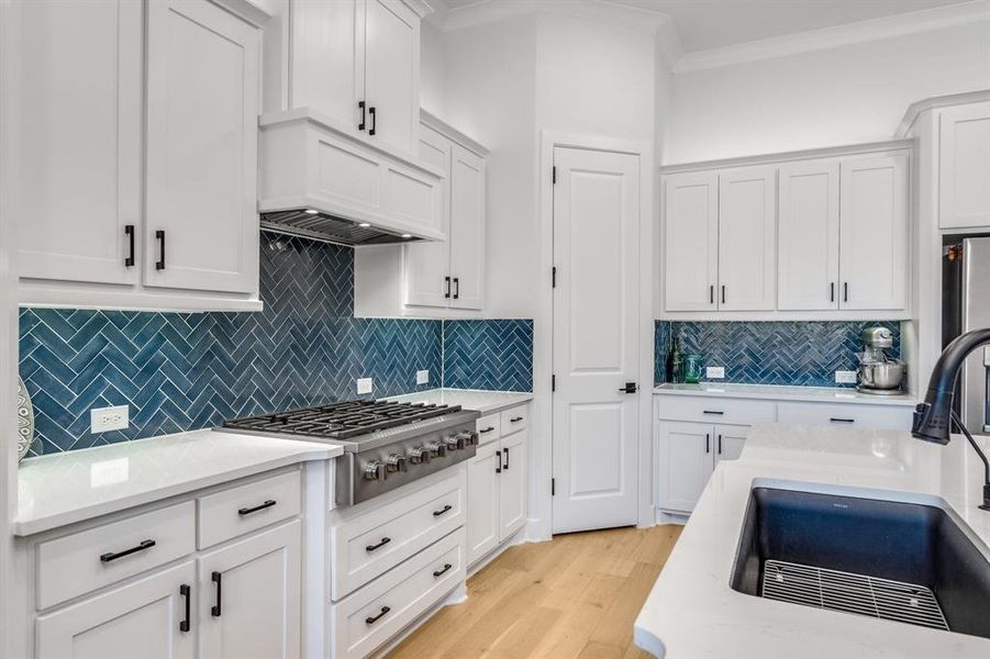 Kitchen featuring white cabinets, stainless steel gas stovetop, decorative backsplash, and sink