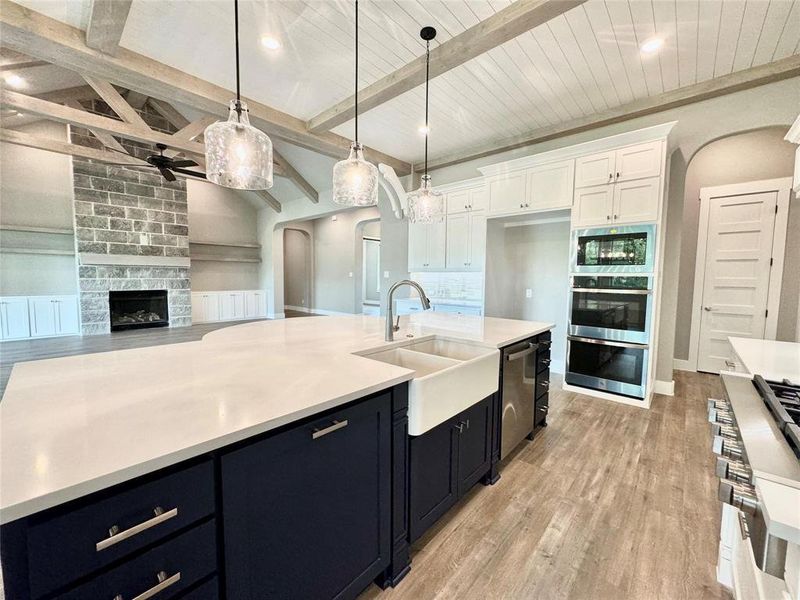 Kitchen featuring a ceiling fan, arched walkways, a sink, appliances with stainless steel finishes, and white cabinets