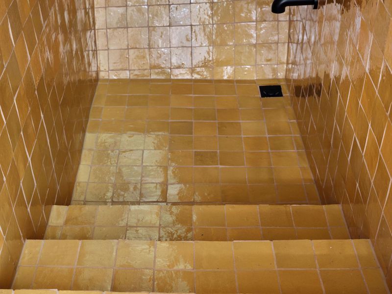 Midcentury Modern Shower/Tub with vibrant saffron hue tile creates an unexpected moment,offering a contrast to the otherwise understated palette.