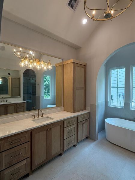 Full bathroom with a chandelier, a soaking tub, vanity, a shower, and high vaulted ceiling