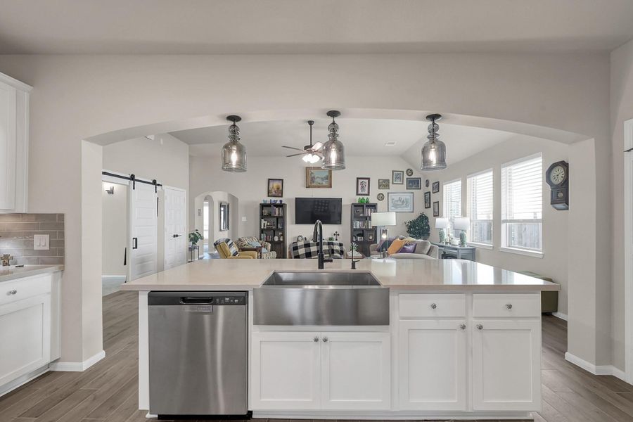 Farmhouse sink situated in the granite countertops and underneath the pendant lighting!