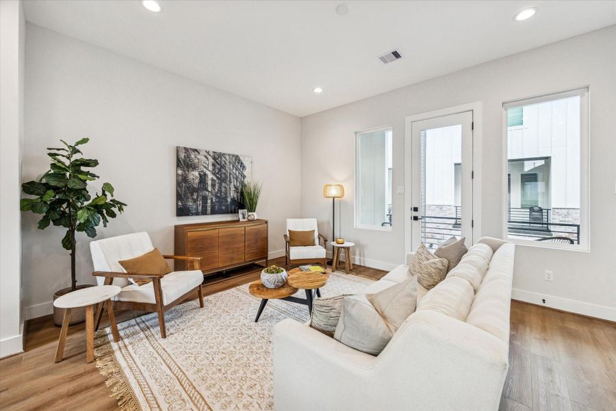 The living room features recessed lighting and is filled with natural light from large windows.