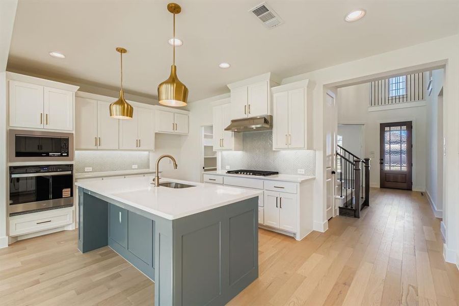 Kitchen featuring white cabinets, appliances with stainless steel finishes, decorative backsplash, light wood-type flooring, and recessed lighting