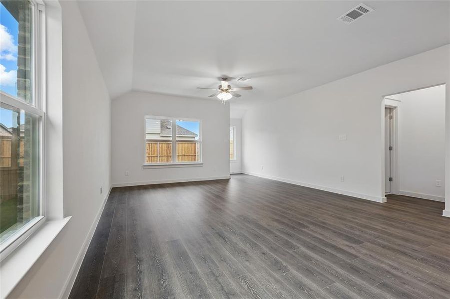 Empty room with a ceiling fan, dark wood-style floors, and vaulted ceiling Empty room with a ceiling fan, dark wood-style floors, and vaulted ceiling
