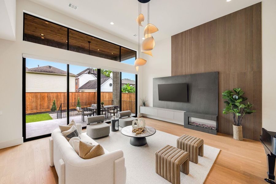 [FAMILY ROOM] Designed to impress, the family room showcases dramatic 14-foot ceilings, a captivating designer light fixture, and an open, airy atmosphere that embodies refined contemporary living.