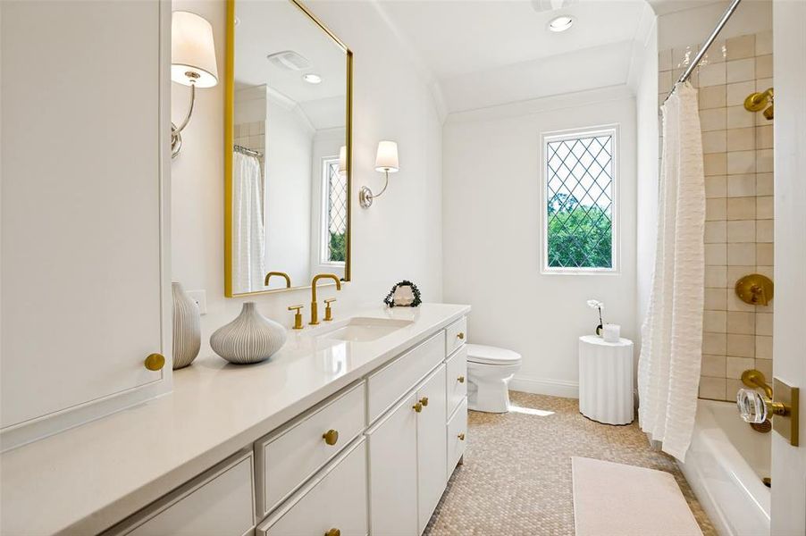 Bathroom featuring an extended vanity with a solid surface countertop, white cabinetry, gold-tone hardware, and a framed mirror
