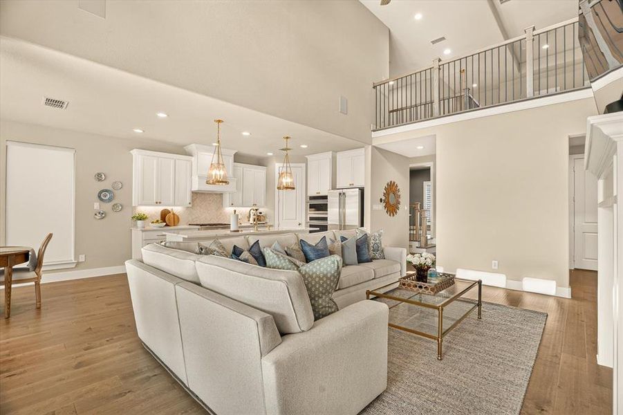 Open-concept living space with a soaring ceiling and wood-finish flooring Open-concept living space with a soaring ceiling and wood-finish flooring