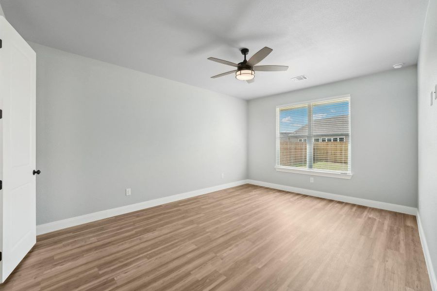 Spare room with visible vents, light wood-style flooring, baseboards, and a ceiling fan