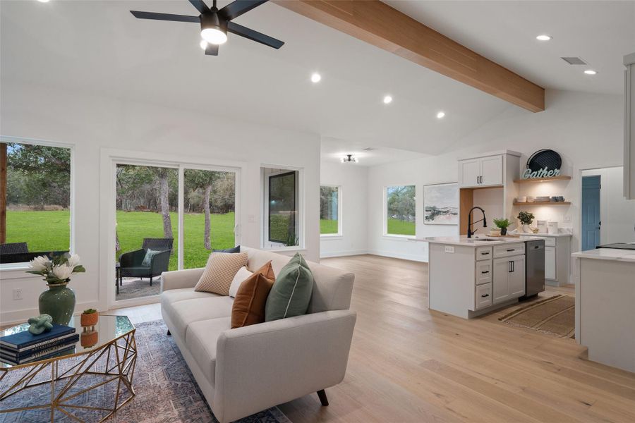 Living room with sink, ceiling fan, high vaulted ceiling, beamed ceiling, and light wood-type flooring