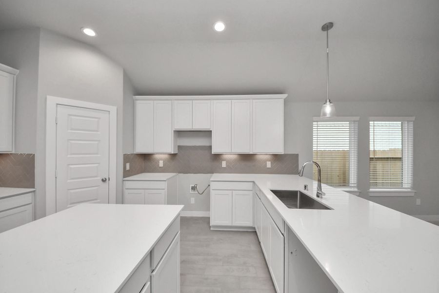 This kitchen is truly a chef's dream! This haven Boasts high ceilings, recessed & pendant lighting, stained wood cabinets, granite countertops, stainless steel appliances, a modern tile backsplash.  All of this overlooks your expansive family room, creating a perfect space for culinary delights and family gatherings. Sample photo of completed home with similar floor plan. Actual colors and selections may vary.