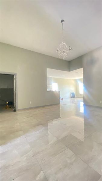 Tiled empty room featuring a notable chandelier and plenty of natural light