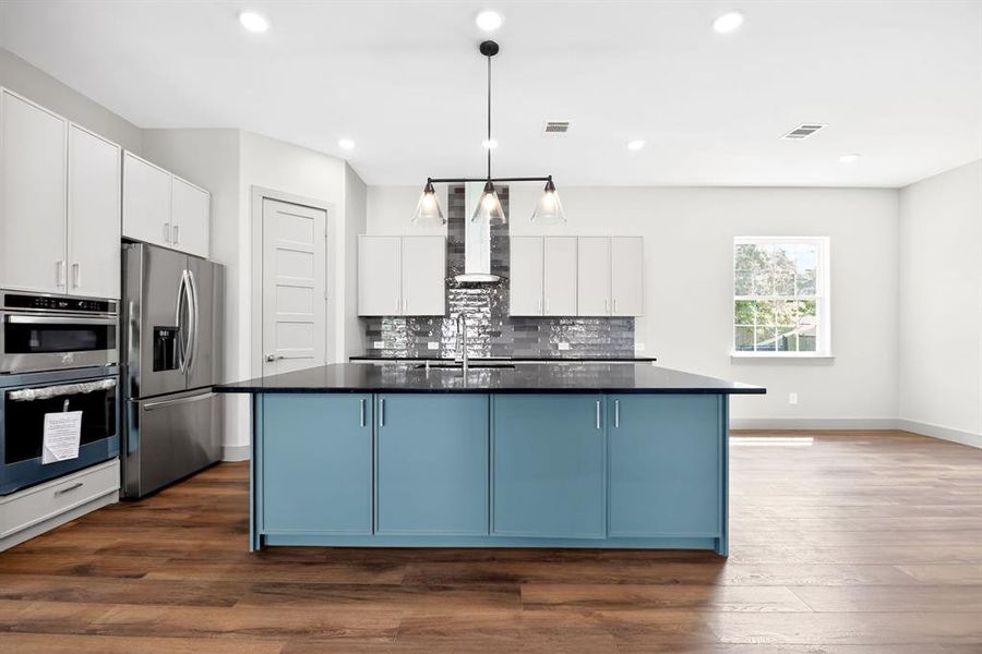 Kitchen with dual tone cabinets, a kitchen island with sink, stainless steel appliances, pendant lighting, and dark wood-type flooring Kitchen with dual tone cabinets, a kitchen island with sink, stainless steel appliances, pendant lighting, and dark wood-type flooring