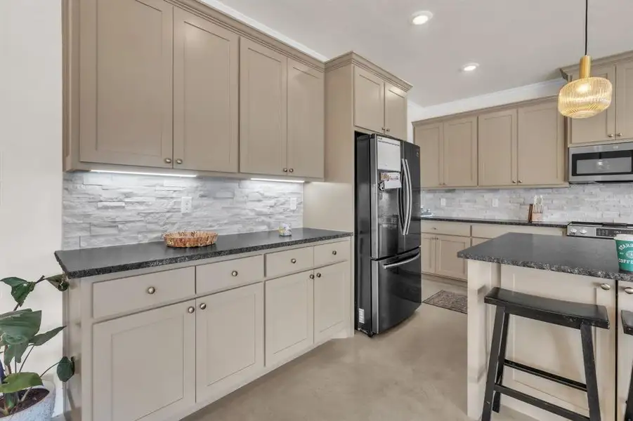 Kitchen with stainless steel appliances, pendant lighting, cream cabinets, concrete floors, and ornamental molding Kitchen with stainless steel appliances, pendant lighting, cream cabinets, concrete floors, and ornamental molding