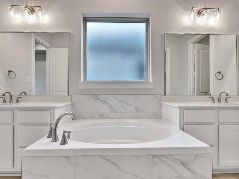 Bathroom with vanity, plenty of natural light, and tiled tub