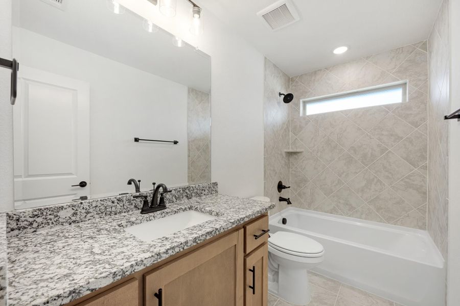 Bathroom with granite vanity, tub-shower combo with diagonal tile surround, and black fixtures Bathroom with granite vanity, tub-shower combo with diagonal tile surround, and black fixtures
