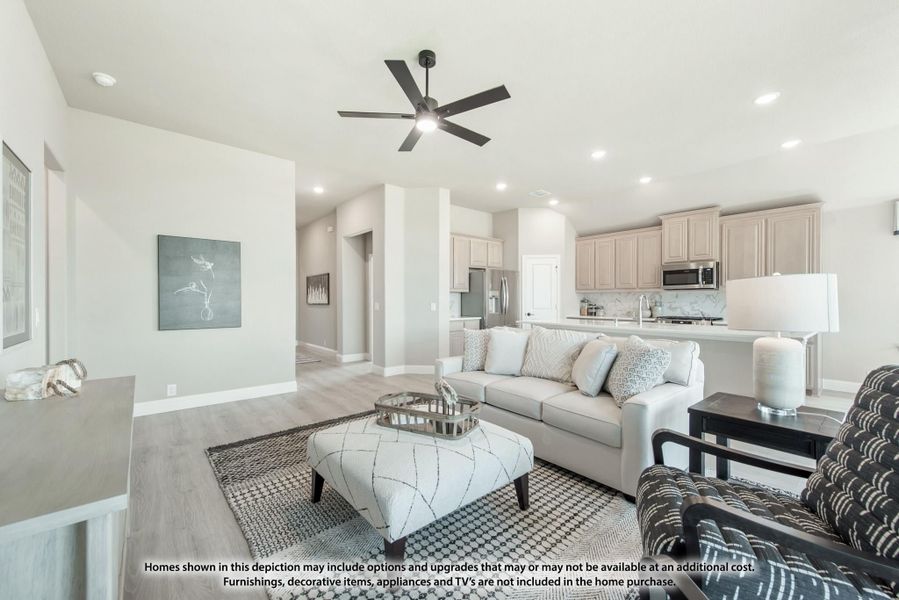 Open-concept living room with ceiling fan and hardwood floors, open to kitchen with light wood cabinets Open-concept living room with ceiling fan and hardwood floors, open to kitchen with light wood cabinets
